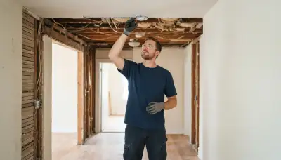 Electrician measures ceiling placement for fire alarm installation in a Louisville, KY home