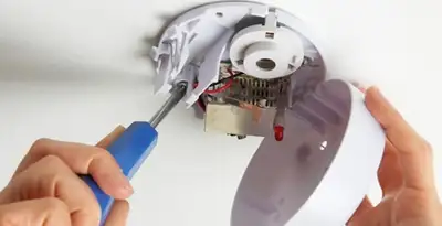 Certified technician wiring smoke detector during installation in Louisville, KY